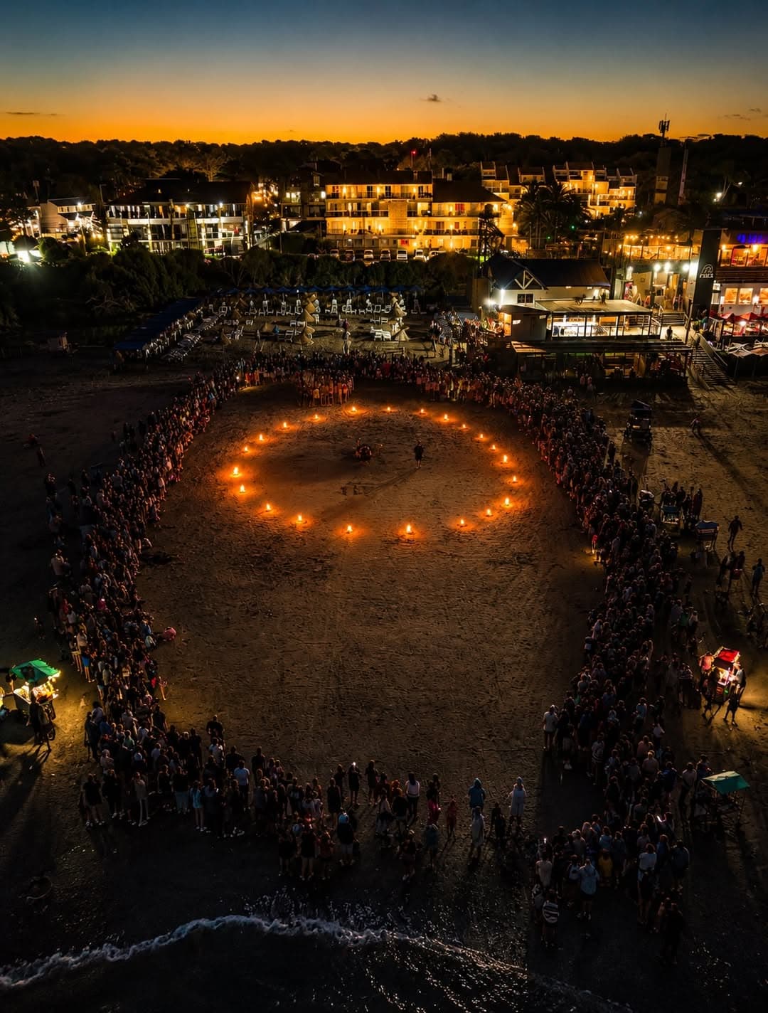 Ronda de fuego de la antorchada vista desde el aire, al anochecer en la playa