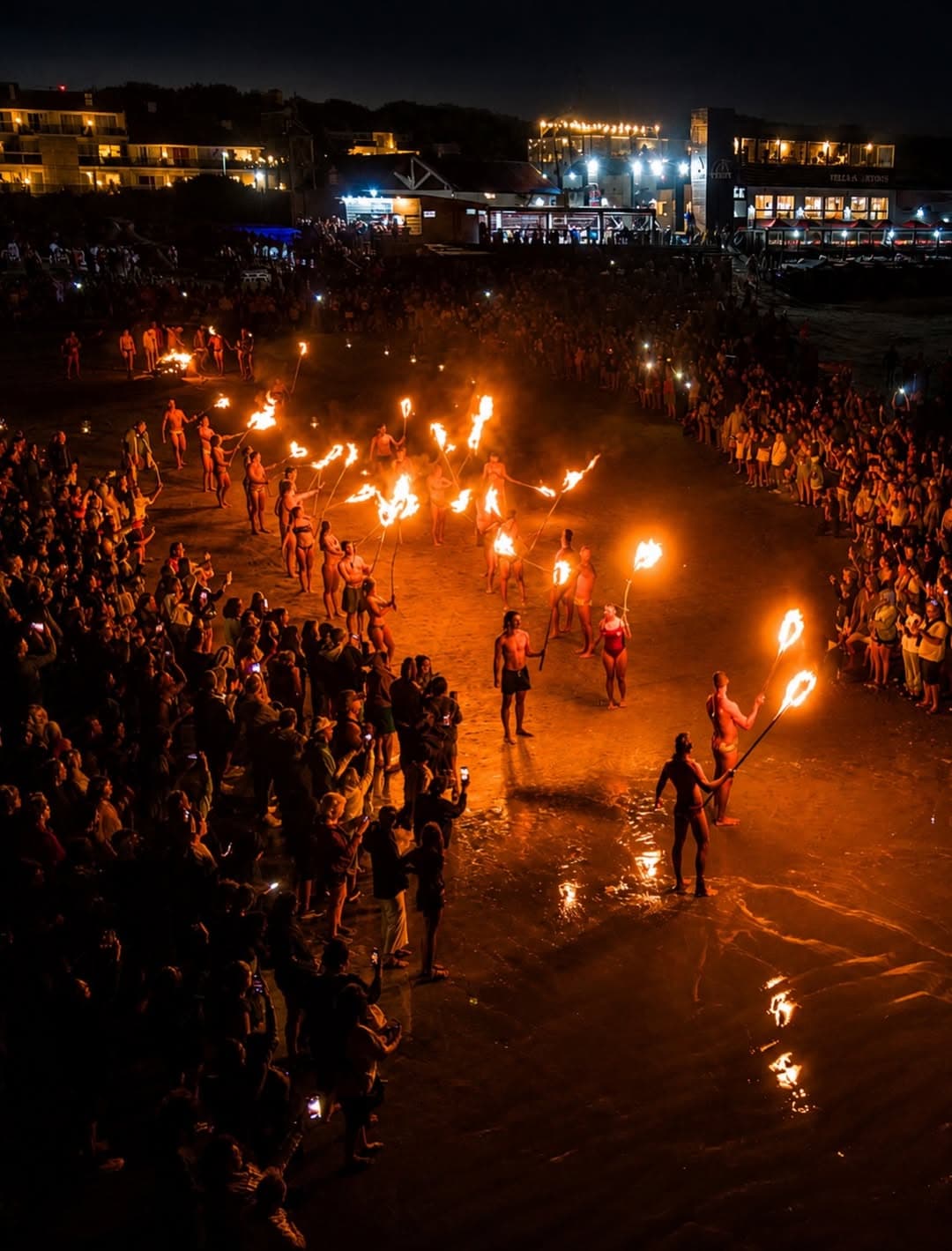 Guardavidas encabezan la caminata de antorchas frente al público en la orilla